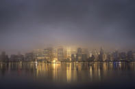 The lights of lower Manhattan burn through the low hanging clouds before sunrise on an overcast morning in New York City, Wednesday, June 19, 2019. (AP Photo/J. David Ake)