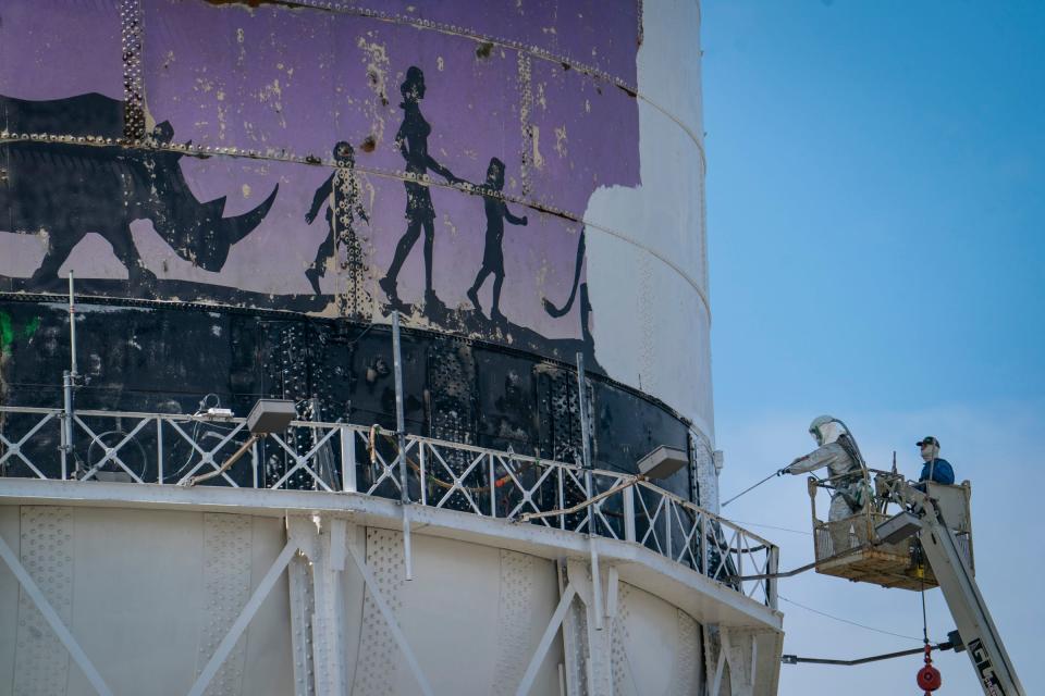 Mike Moran, owner of Protective Coatings Epoxy Systems in Fowlerville, left, leans in with a sprayer as Guy Bajis, right, assists on the iconic Detroit Zoo water tower in Royal Oak that is getting a facelift Thursday, June 22, 2023.