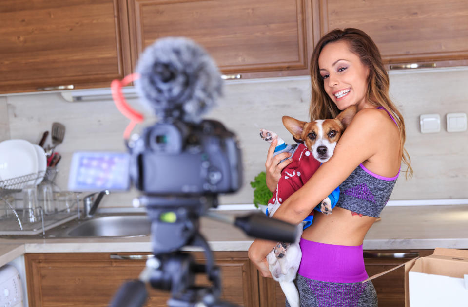 A woman filming herself with her dog