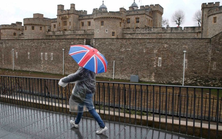 A tourist carrying a Union Flag umbrella walks in the rain during a spell of wet weather, next to The Tower of London, in London, Britain January 15, 2017 - PETER NICHOLLS 