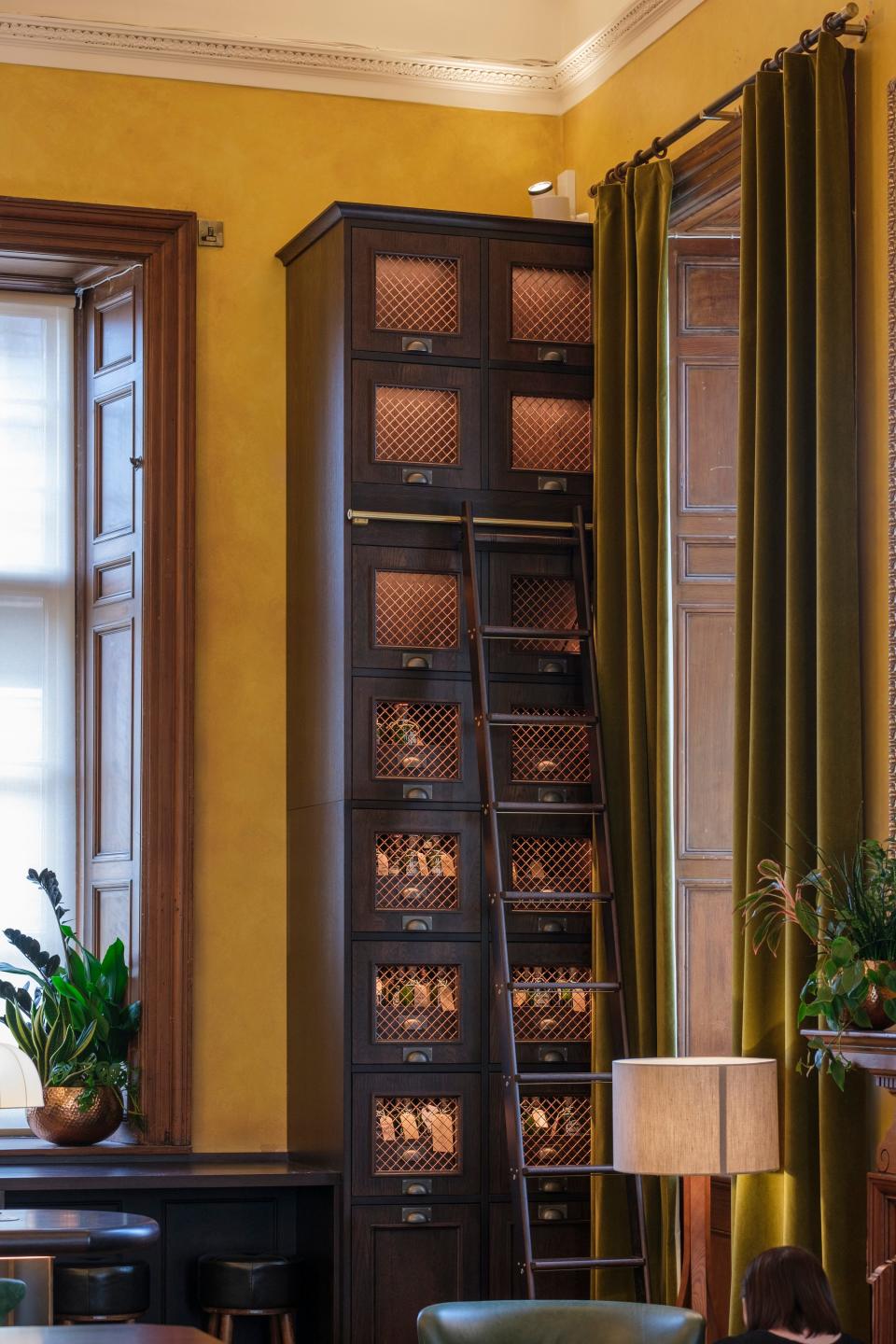 A stack of wooden cupboards with glass windows in a yellow room.