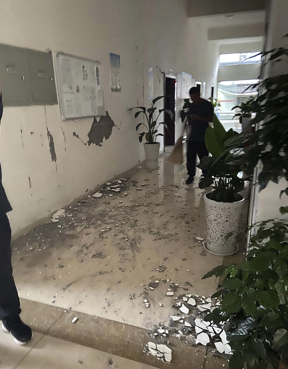 In this photo provided by Qiu Xin, people sweep up debris in the hallway of an office building after an earthquake in Luzhou in southwestern China's Sichuan Province, Thursday, Sept. 16, 2021. Rescue work was underway following a magnitude-6.0 earthquake early Thursday in southwest China's Sichuan province. (Qiu Xin via AP)