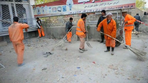 City workers clear the scene of a car suicide attack near the building from which insurgents attacked in front of the parliament in Kabul