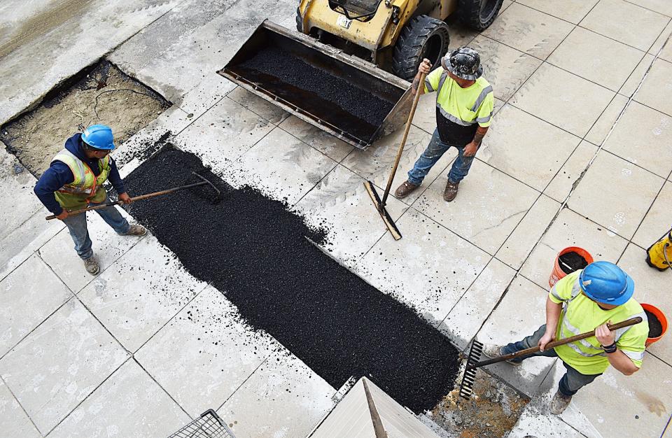 Workers patch the sidewalk at Fall River's Government Center on Wednesday.