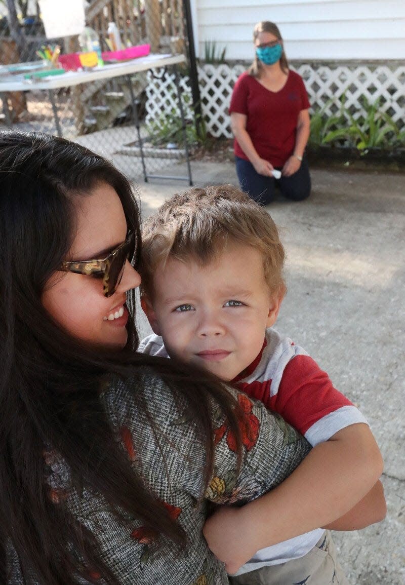 Sasha Staton hugs her 3-year-old son, Nash, as teacher Denise Mueller waits to check his temperature before he can be dropped off at Imagination Station in Daytona Beach.