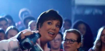 Kris Jenner holding a camcorder in a scene from an Ariana Grande music video