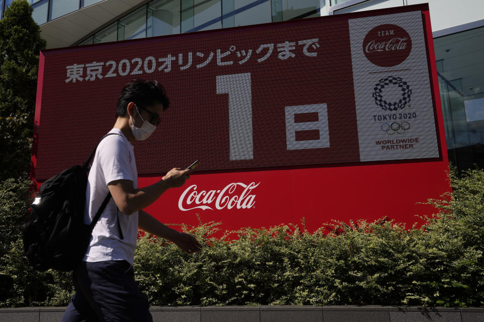 A pedestrian passes by a large electronic display shows one day until the opening ceremony of 2020 Tokyo Olympics, Thursday, July 22, 2021, in Tokyo. (AP Photo/Kiichiro Sato)