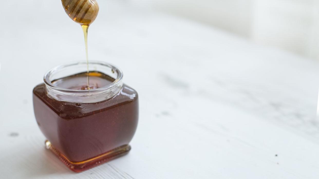 pouring honey into jar of honey