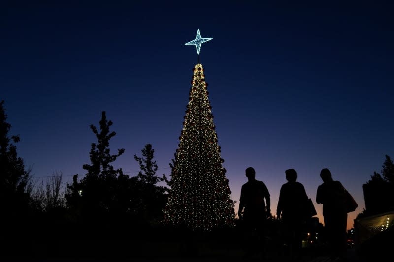 People walk in front of a Christmas tree on a street at dusk. Matias Basualdo/ZUMA Press Wire/dpa