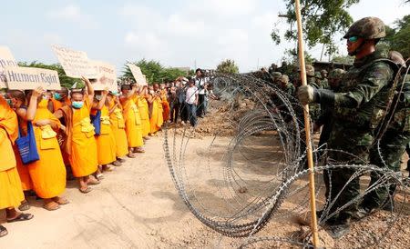 Buddhist monks stand in front of soldiers between a wire barricade at Dhammakaya temple, in Pathum Thani province, Thailand February 23, 2017. REUTERS/Chaiwat Subprasom