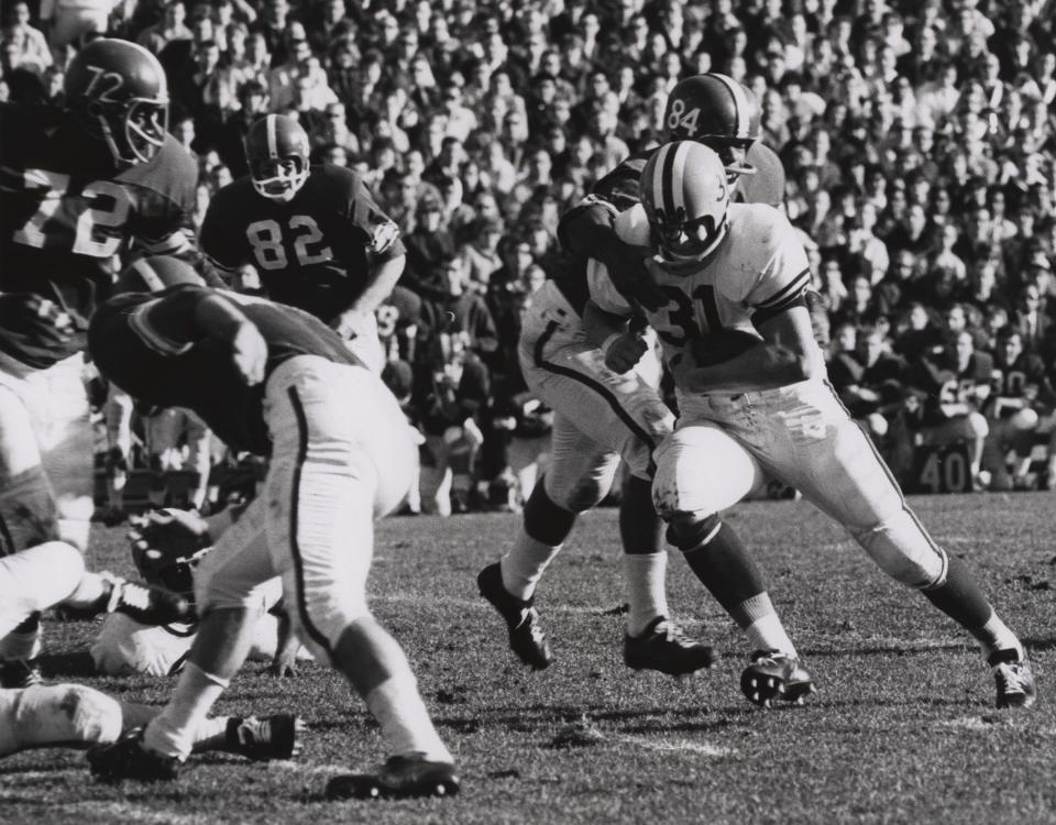 Illinois running back Jim Grabowski (31) escapes the tackle of Michigan State defensive end Matthew Snorton (84) on Nov. 28, 1963 in East Lansing.