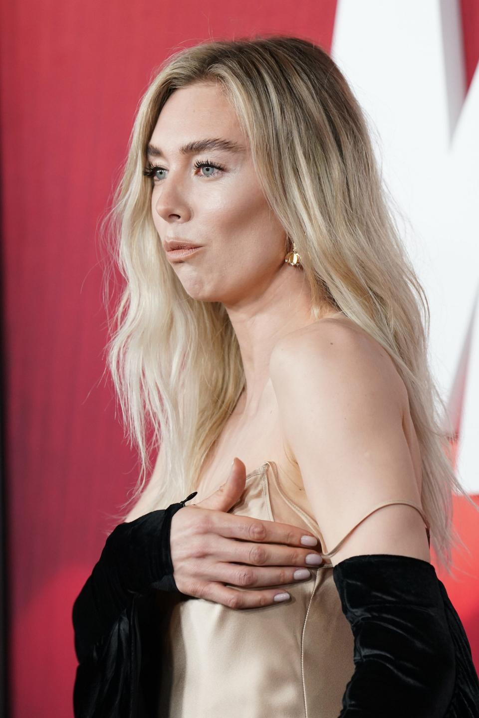 Vanessa Kirby holds her dress in place on a red carpet.