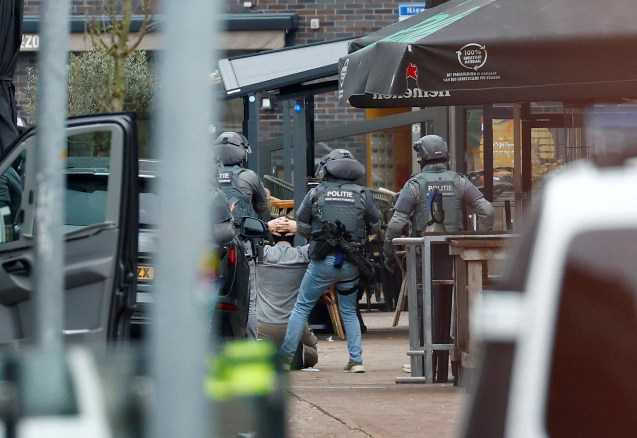 Dutch police officers detain a person outside the Cafe Petticoat, where several people were being held hostage in Ede (REUTERS)