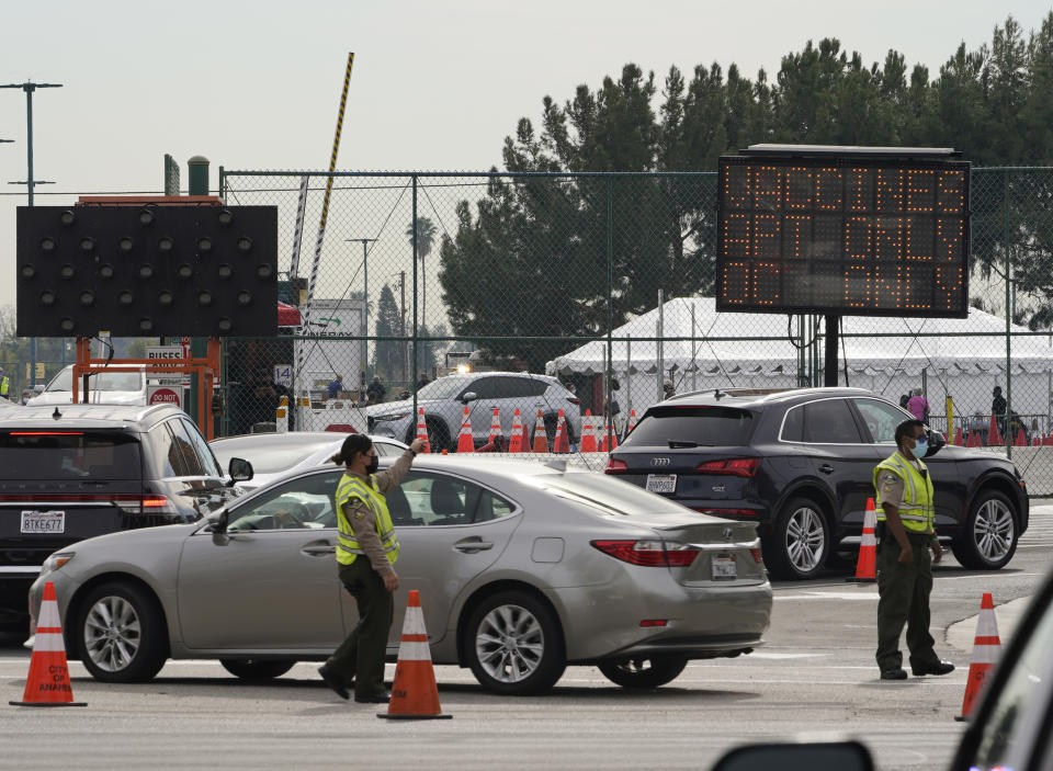 Vehicles queue up outside the Disneyland Resort parking for a COVID-19 vaccine in Anaheim, Calif., Wednesday, Jan. 13, 2021. The parking lot is located off Katella Avenue and sits southeast of Disneyland. California is immediately allowing residents 65 and older to get scarce coronavirus vaccines, Gov. Gavin Newsom announced Wednesday. (AP Photo/Damian Dovarganes)