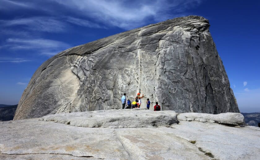 File - In this July 15, 2014, file photo, hikers gather in the foreground as climbers use the assistance of cables to scale Half Dome in Yosemite National Park National Park in California's Sierra Nevada. A hiker in Yosemite National Park fell to his death while climbing to the top of iconic granite cliffs of Half Dome. Park spokesman Scott Gediman says 29-year-old Danielle Burnett, of Lake Havasu City, Arizona, was scaling the steepest part of the trail Thursday, Sept. 5, 2019, when she fell more than 500 feet down the steep, rocky terrain. Gediman says Burnett was dead when Park Rangers arrived on the scene. (AP Photo/Brian Melley, File)