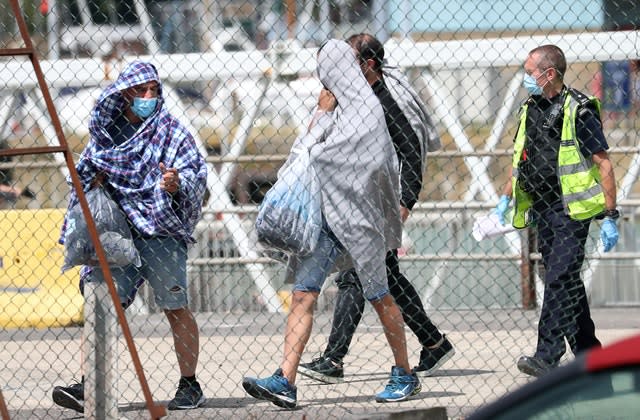 Men thought to be a migrants are escorted to waiting vehicles (Gareth Fuller/PA)