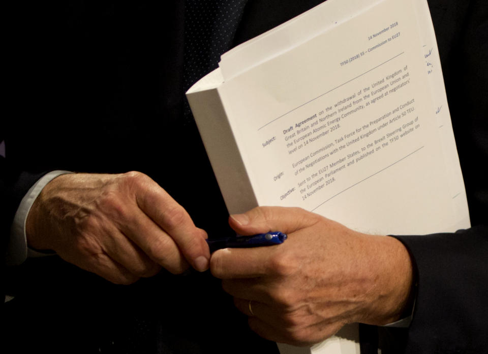 EU chief Brexit negotiator Michel Barnier holds the draft withdrawal agreement during a media conference in Brussels on Wednesday, Nov. 14, 2018. EU ambassadors met in Brussels Wednesday, in a closed door session, to discuss the draft agreement. (AP Photo/Virginia Mayo)