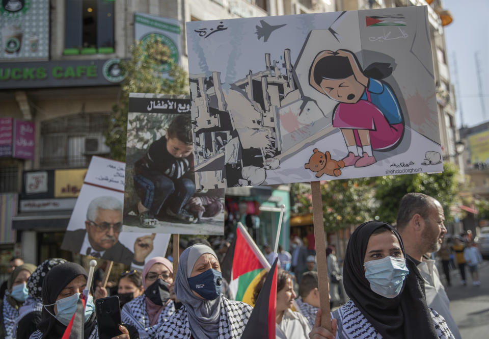 Palestinian women carry posters that read "no for terrorizing the children, Gaza, Palestine," during a protest supporting the children in Gaza, in the West Bank city of Ramallah, Thursday, May 20, 2021. (AP Photo/Nasser Nasser)