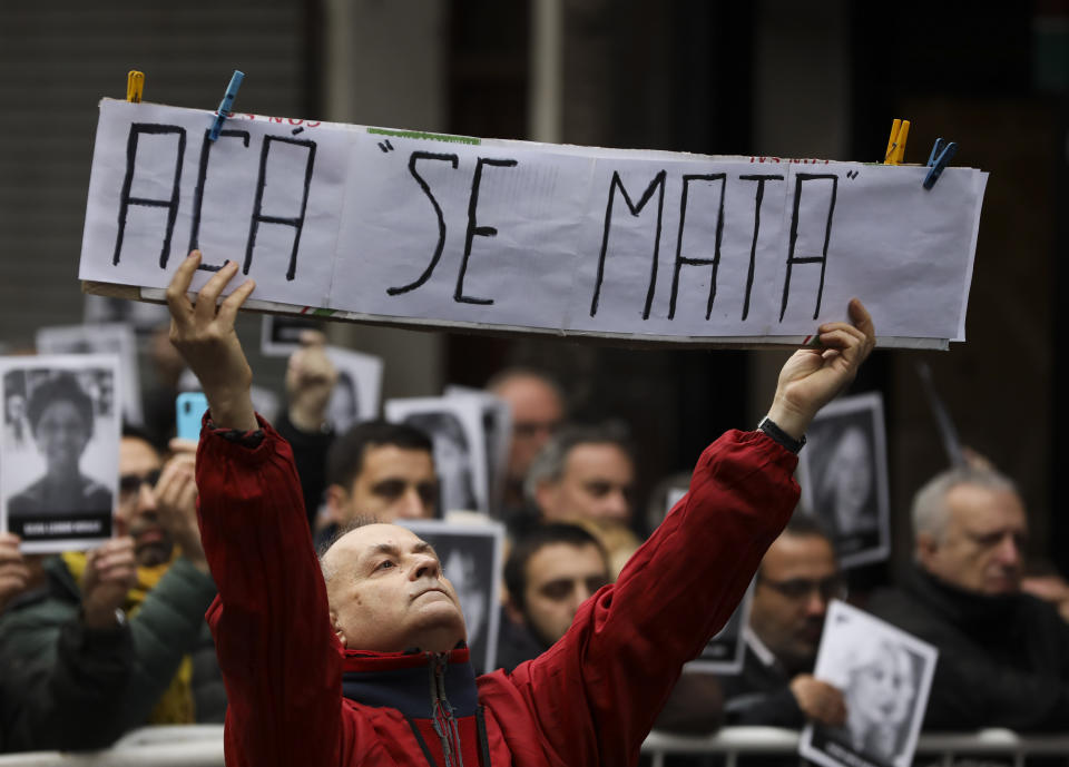 A man holds the Spanish message: "Here they kill" on the 25 anniversary of the bombing of the AMIA Jewish center that killed 85 people in Buenos Aires, Argentina, Thursday, July 18, 2019. (AP Photo/Natacha Pisarenko)