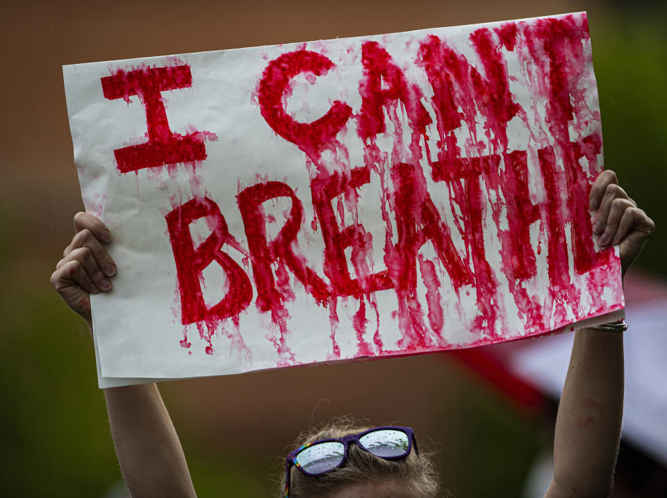 Eine Frau hält während einer "Black Lives Matter"-Kundgebung in der Innenstadt ein Plakat mit der Aufschrift "I can't breathe" in die Höhe, während die roten Buchstaben im Regen zerlaufen. Foto: Christian Murdock / The Gazette / AP / dpa