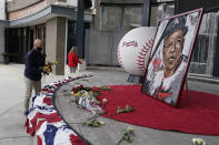 Atlanta Braves employees place flowers next to a portrait Atlanta Braves' Hank Aaron outside Truist Park, Friday, Jan. 22, 2021, in Atlanta. Aaron, who endured racist threats with stoic dignity during his pursuit of Babe Ruth but went on to break the career home run record in the pre-steroids era, died peacefully in his sleep early Friday. He was 86. (AP Photo/John Bazemore