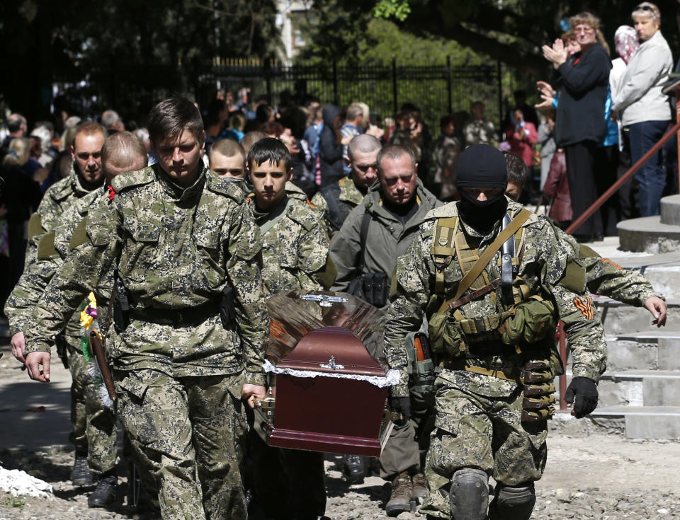 Pro-Russian gunmen carry the coffin of a person killed during last week's operation, during a commemorative service in the center of Slovyansk, eastern Ukraine, Wednesday, May 7, 2014. The U.S. and European nations have increased diplomatic efforts ahead of Ukraine's May 25 presidential election, as a pro-Russian insurgency continues to rock the country's eastern regions. (AP Photo/Darko Vojinovic)