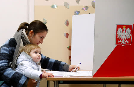 A woman with a child casts her vote during the Polish regional elections, at a polling station in Warsaw, Poland, October 21, 2018. REUTERS/Kacper Pempel