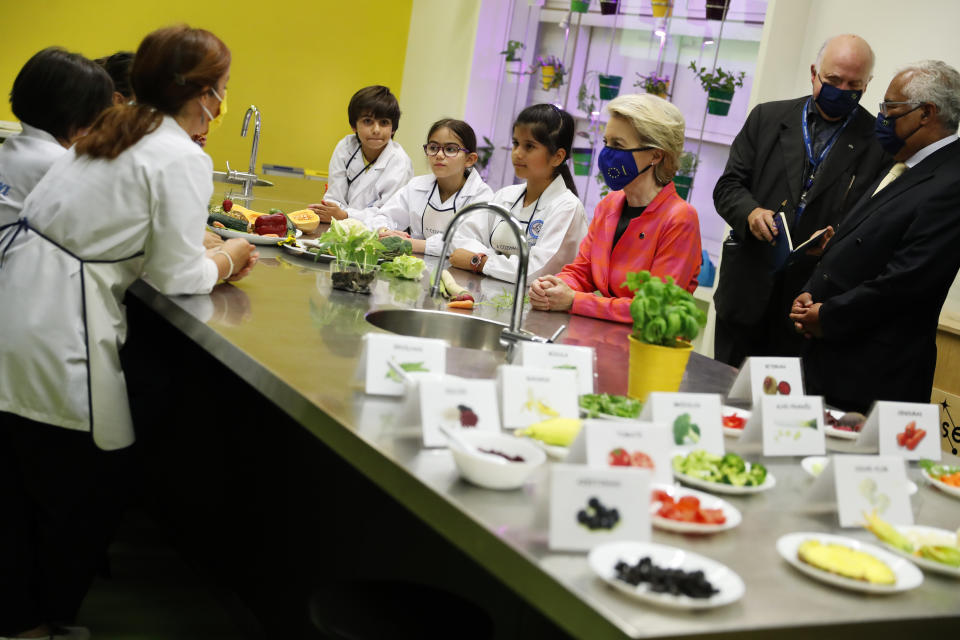 European Commission President Ursula von der Leyen, center, and Portuguese Prime Minister Antonio Costa, right, join schoolchildren in a kitchen lab at the Center for Living Science in Lisbon, Wednesday, June 16, 2021. The president of the European Commission has started in Lisbon a tour of some European Union capitals to announce the initial endorsement of their plans for spending the bloc's massive economic recovery fund. (AP Photo/Armando Franca)