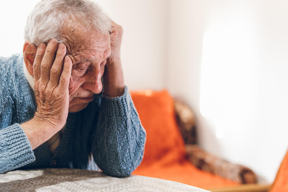 An old man sitting at a table with his head in his hands