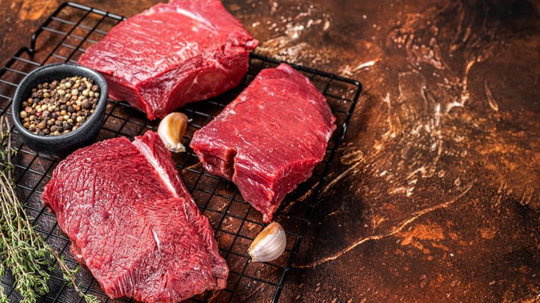 Three raw venison steaks by peppercorns