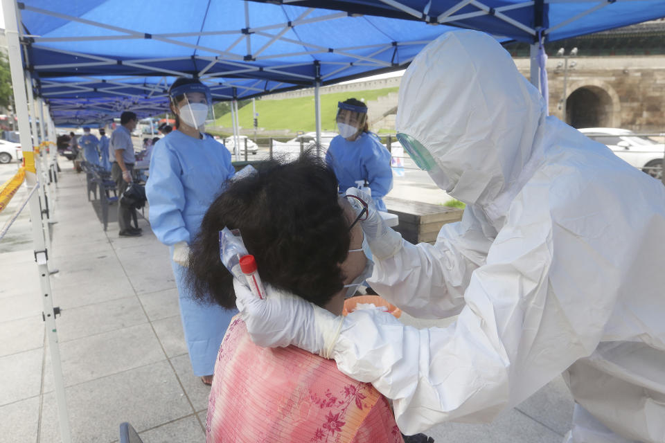 A health official wearing protective gear takes samples from a woman during the COVID-19 testing at a makeshift clinic in Seoul, South Korea, Monday, Aug. 10, 2020. (AP Photo/Ahn Young-joon)