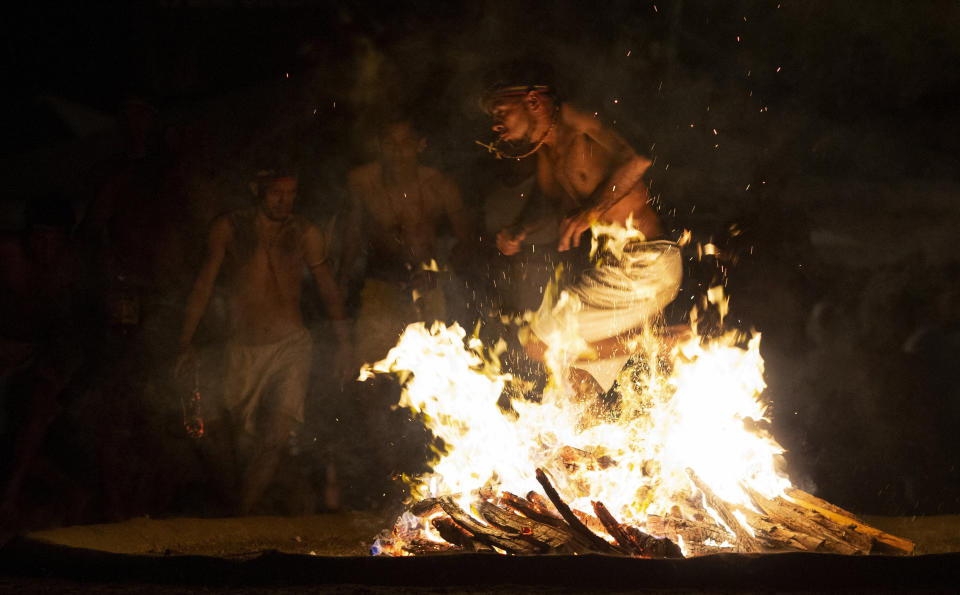 In this photo taken Oct. 11, 2019, a man performs the flame dance on Sorte Mountain where followers of indigenous goddess Maria Lionza gather annually in Venezuela's Yaracuy state. Those immersed in the old tradition say it puts them in a trance that allows them to channel spirits and escape injury from otherwise dangerous feats. (AP Photo/Ariana Cubillos)