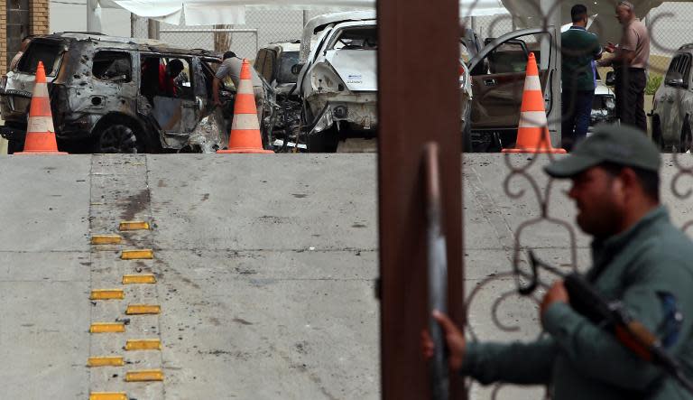 Iraqi security examine the wreckage of cars at the Babylon hotel in Baghdad on May 29, 2015, after a car bomb ripped through the parking lot early in the morning