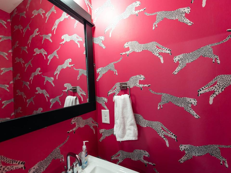 A bathroom wall with pink, cheetah-print wallpaper.