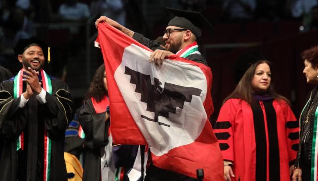 Jos&#xe9; Fern&#xe1;ndez, who earned a degree in business, unfurls the United Farm Workers flag during the 47th Chicano/Latino Commencement Celebration at the Save Mart Center on May 20, 2023.