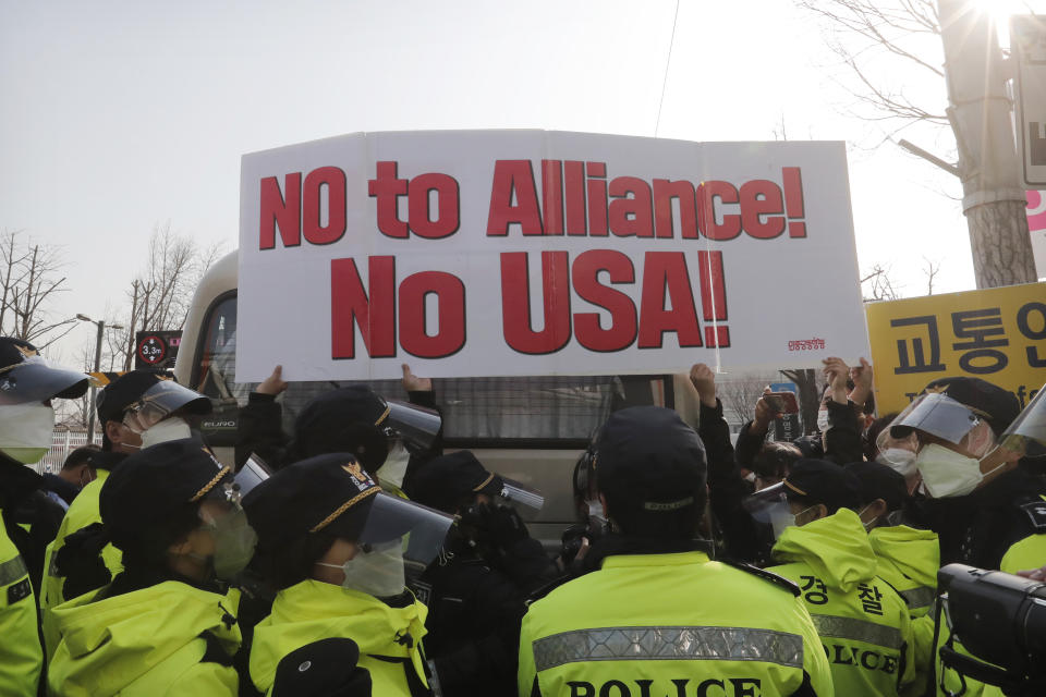 Protesters hold up a banner during a rally against a visit of U.S. Defense Secretary Lloyd Austin and Secretary of State Antony Blinken as police stand guard outside Foreign Ministry in Seoul, South Korea, Thursday, March 18, 2021. North Korea said Thursday it will ignore a U.S. offer for talks unless it withdraws its hostile policy, days after Washington reached out to Pyongyang in a bid to resume nuclear negotiations. (AP Photo/Ahn Young-joon)