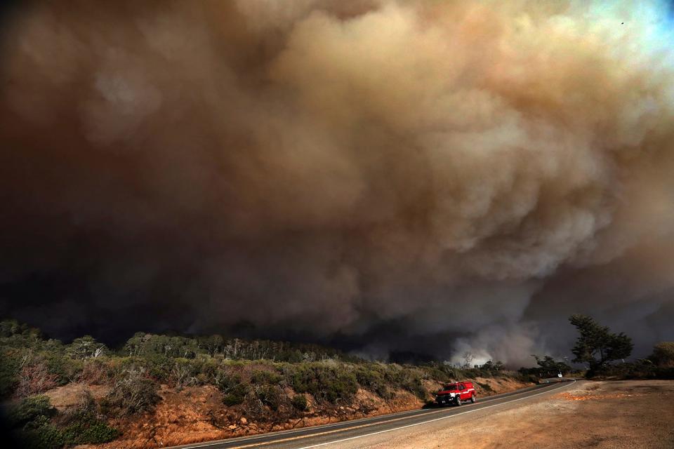 A massive column of smoke rises above Highway 1 just north of the Santa Cruz County line as a section of the CZU August Lightning Complex burns above Waddell Beach on Aug. 19, northwest of Santa Cruz, Calif.