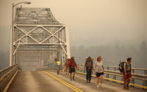 <p>Pedestrians walk off the Bridge of the Gods, which spans the Columbia River between Washington and Oregon states, as smoke from the Eagle Creek wildfire obscures the Oregon hills in the background near Stevenson, Wash., on Sept. 6, 2017. (Photo: Randy L. Rasmussen/AP) </p>