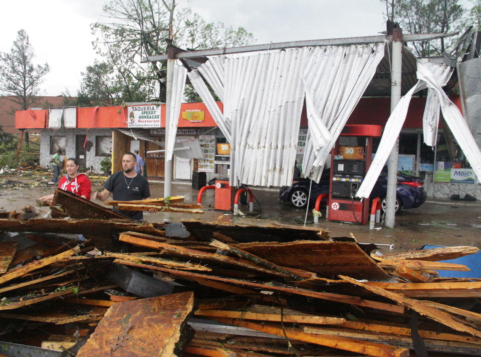 Esmeralda, left and Craig Stanford help a friend clean up his North Gloster Street Texaco gas station and quick stop in Tupelo, Miss, after a tornado touched down on Monday, April 28, 2014. (AP Photo/Jim Lytle)