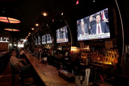 A man watches a television showing former FBI director James Comey's testimony before the Senate Intelligence Committee, in Tonic bar in New York City, U.S., June 8, 2017. REUTERS/Joe Penney