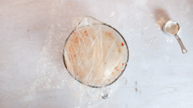 hot honey sourdough in bowl, covered with plastic wrap