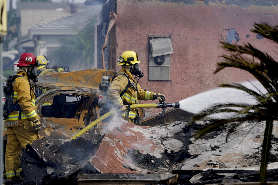 Fire crews work the scene of a small plane crash, Monday, Oct. 11, 2021, in Santee, Calif. At least two people were killed and two others were injured when the plane crashed into a suburban Southern California neighborhood, setting two homes ablaze, authorities said. (AP Photo/Gregory Bull)