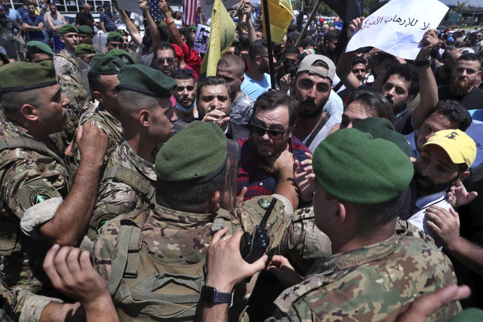 Hezbollah supporters scuffle with Lebanese army soldiers while protesting the visit to Lebanon by Gen. Frank McKenzie, the head of US Central Command, outside the Rafik Hariri International Airport in Beirut, Lebanon, Wednesday, July 8, 2020. The Arabic placard that reads, "No to American terrorism." (AP Photo / Bilal Hussein)