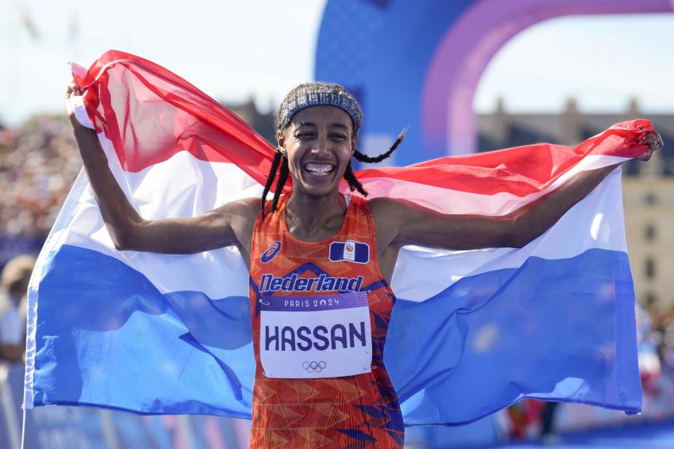 Olympic runner Sifan Hassan holds up a Dutch flag.