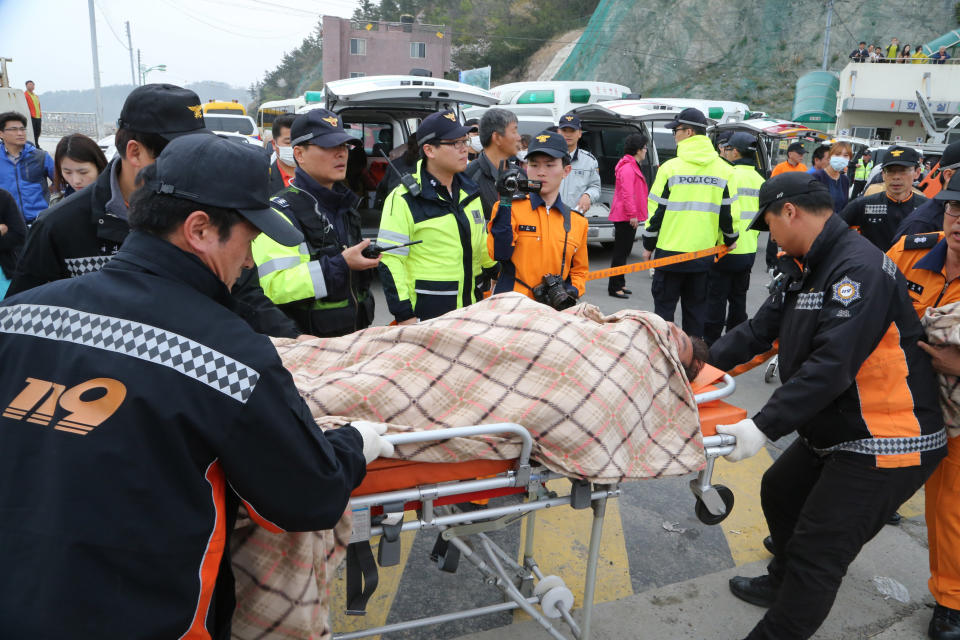 A rescued passenger from a ferry sinking off South Korea's southern coast, is carried by rescue teams on his arrival at Jindo port in Jindo, south of Seoul, South Korea, Wednesday, April 16, 2014. Dozens of military boats and helicopters scrambled Wednesday to rescue more than 470 people, including 325 high school students on a school trip, after the ferry sank off South Korea's southern coast, officials said. (AP Photo/Park Chul-heung, Yonhap) KOREA OUT