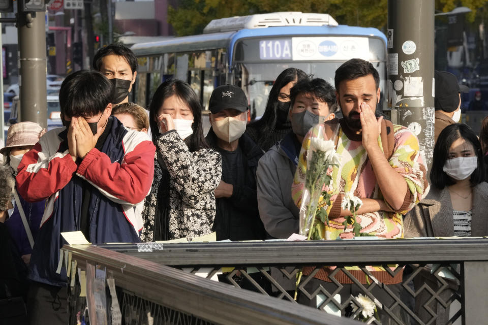 People weep as they pay tribute to victims of a deadly accident following Saturday night's Halloween festivities on the street near the scene in Seoul, South Korea, Tuesday, Nov. 1, 2022. (AP Photo/Ahn Young-joon)