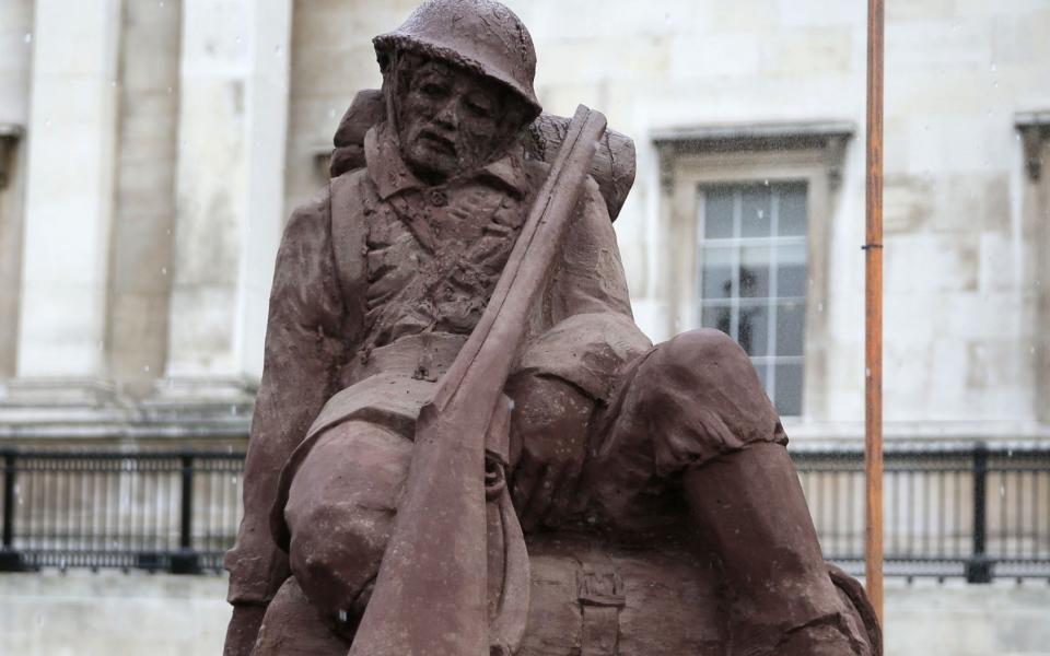 Passers-by look at the 'Mud Soldier' statue, which is sculpted from sand and mud from Passchendaele, during the unveiling ceremony on the North Terrace of Trafalgar Square in central London on July 25, 2017, the centenary of the Battle of Passchendaele. 'The Mud Soldier' will slowly dissolve over the course of four days, a representation of the rain and mud so closely associated with the battle 100 years ago.  - DANIEL LEAL-OLIVAS/AFP/Getty Images