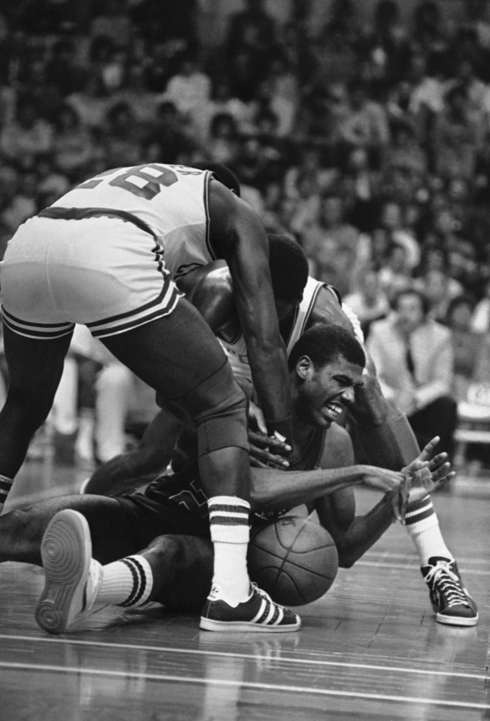 Milwaukee Buck Paul Pressey, center, reacts as he struggles for a loose ball against Boston Celtics Robert Parish, behind, and Quinn Buckner, in front, during first period NBA playoff action at the Boston Garden, May 17, 1984. (AP Photo/Mike Kullen)