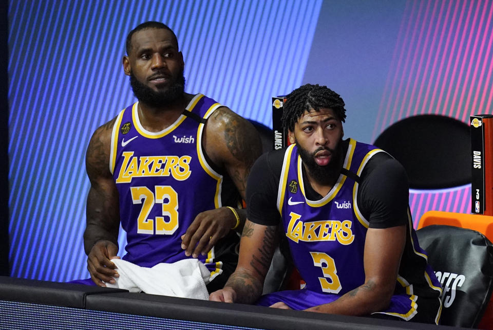 LeBron James, left, in a purple No. 23 Lakers jersey and Anthony Davis, next to him on the bench, in the No. 3.