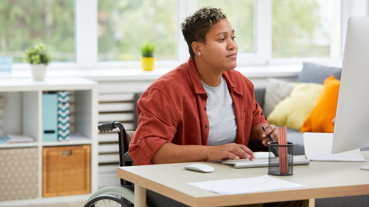  A person in a wheelchair working at a computer. 